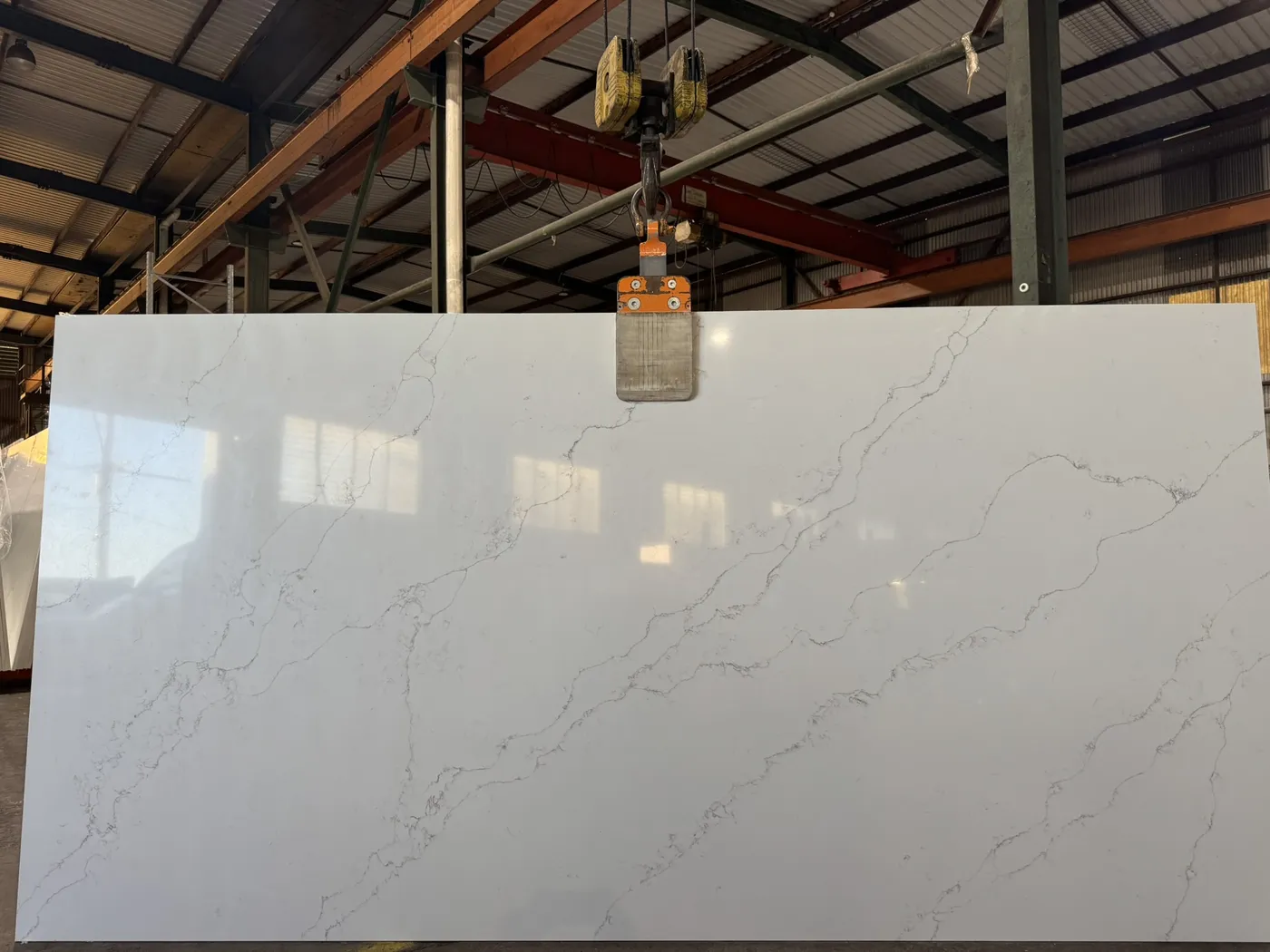 A white veined slab standing in a warehouse aisle under high racking