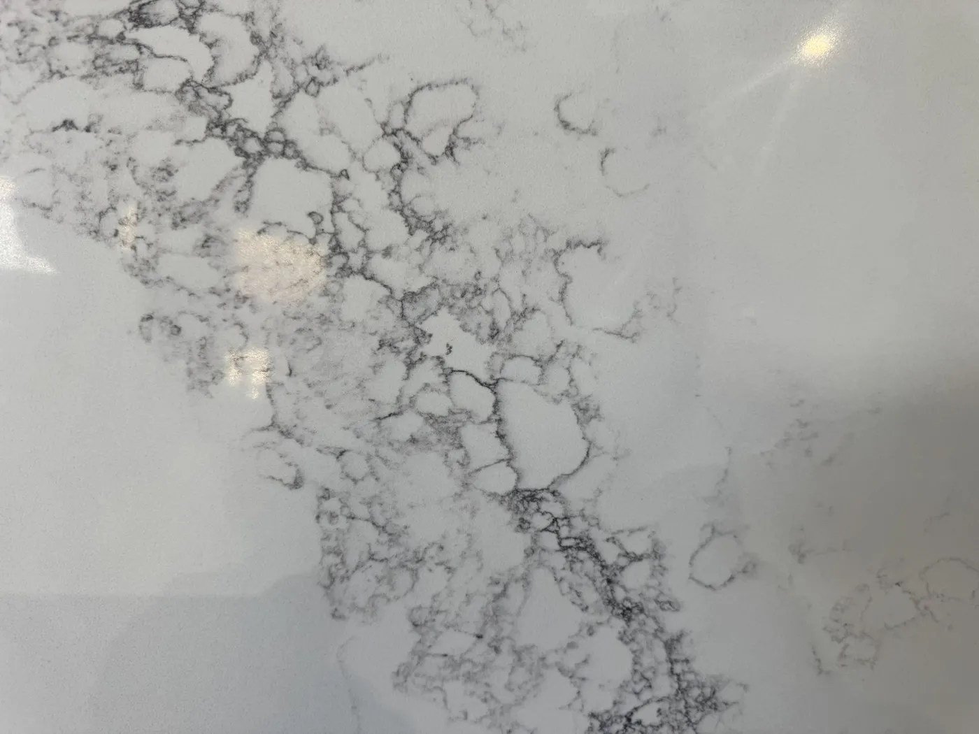 Branching grey veins across a white slab surface